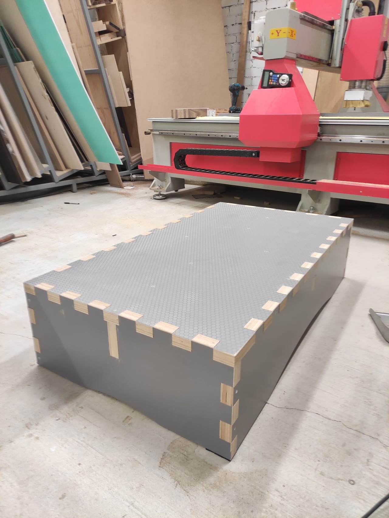 Grey plywood box with finger joints on a workshop floor