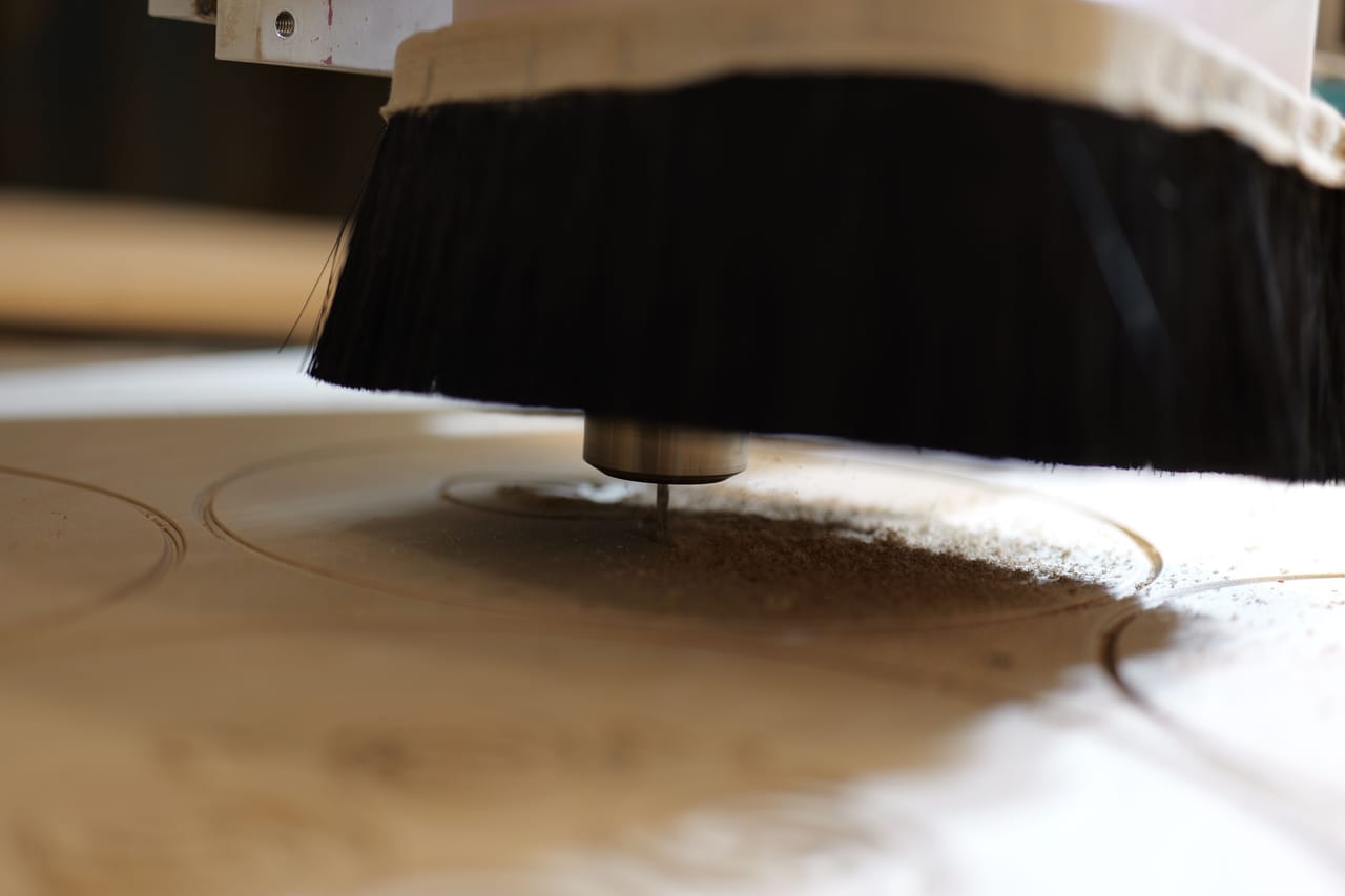 CNC router bit cutting plywood with a dust brush