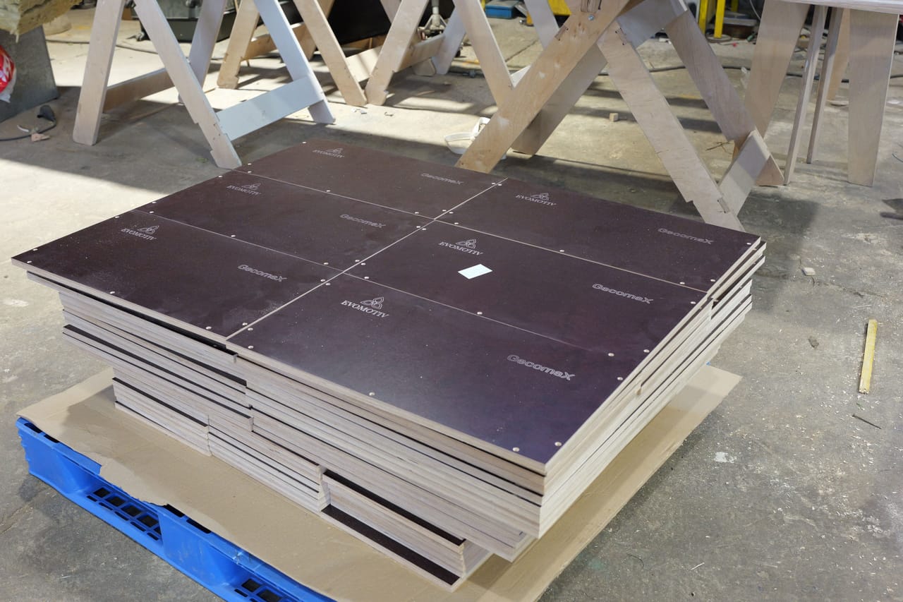 Stack of film-faced plywood parts with engraved panels on a blue pallet
