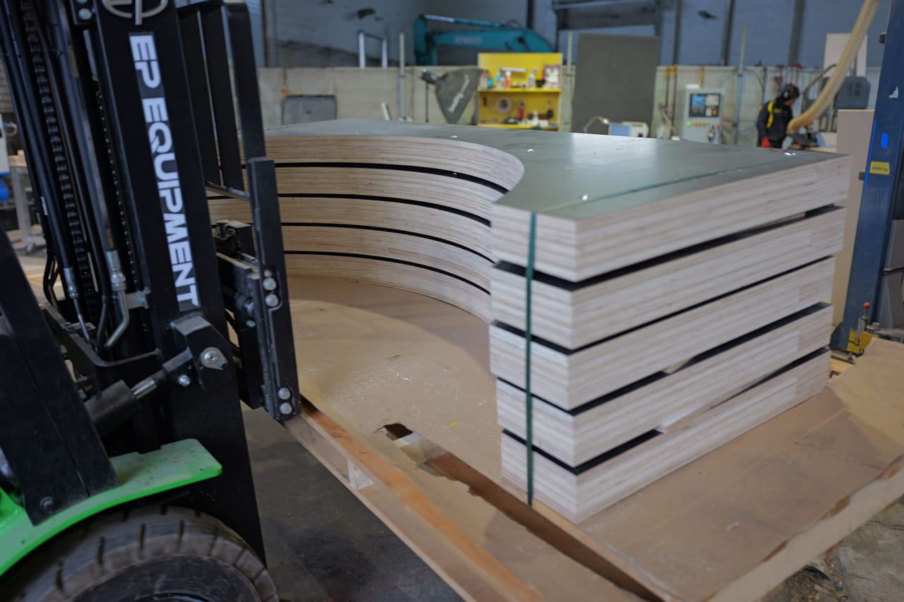 Stack of curved plywood parts on a pallet, second angle